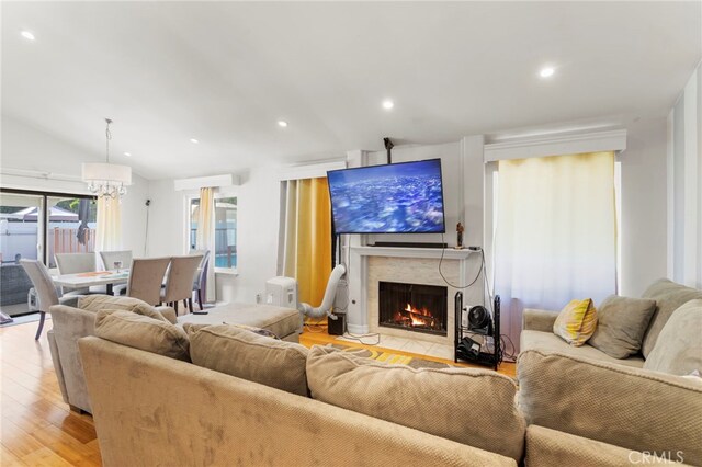 living room featuring light hardwood / wood-style flooring, lofted ceiling, and a premium fireplace