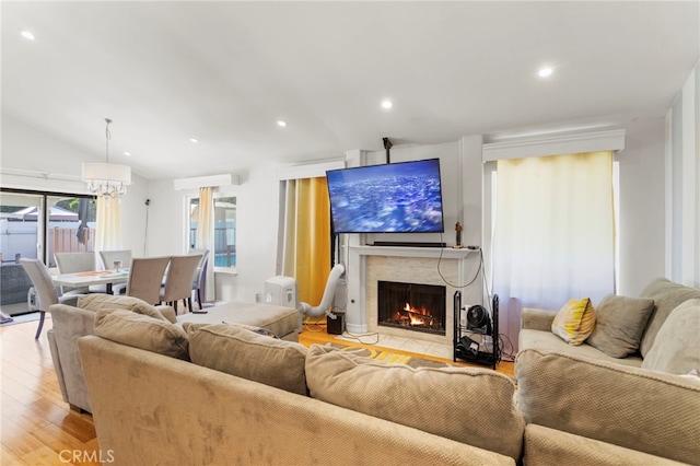 living area featuring light wood-style floors, recessed lighting, a high end fireplace, a chandelier, and vaulted ceiling