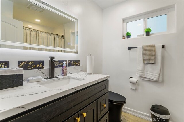 bathroom with toilet, vanity, and walk in shower