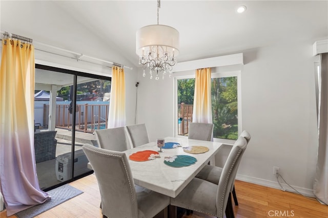 dining area with baseboards, a chandelier, lofted ceiling, and light wood finished floors