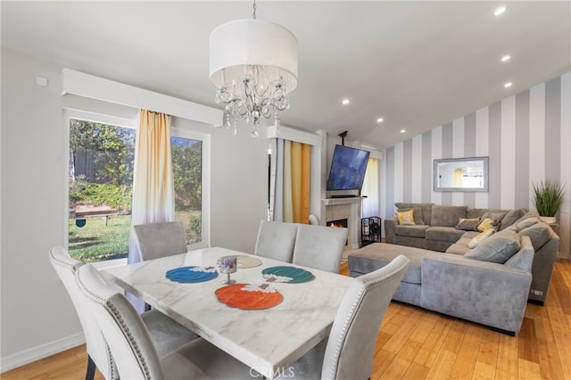 dining room with an inviting chandelier, vaulted ceiling, and light wood-type flooring