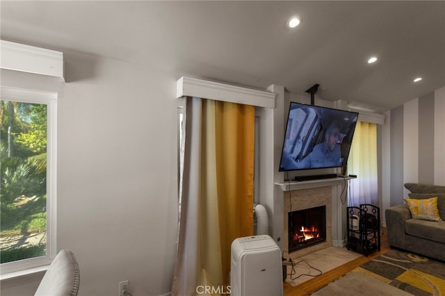 living room with hardwood / wood-style floors, a healthy amount of sunlight, and a tiled fireplace