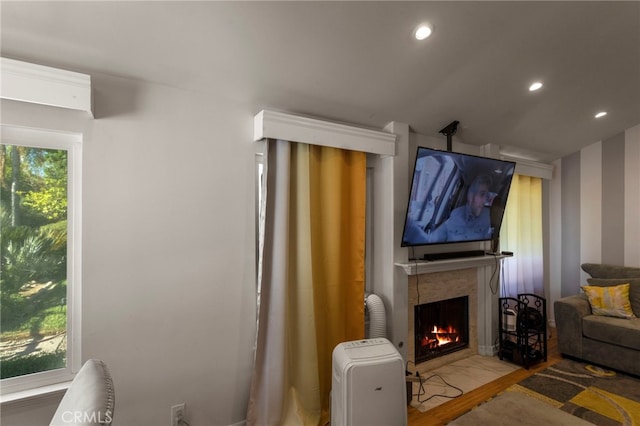 living area with recessed lighting, a fireplace with flush hearth, and wood finished floors