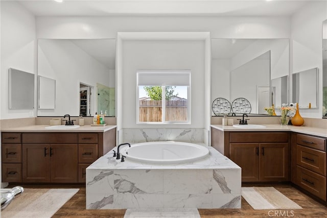 bathroom with vanity, hardwood / wood-style floors, and tiled tub