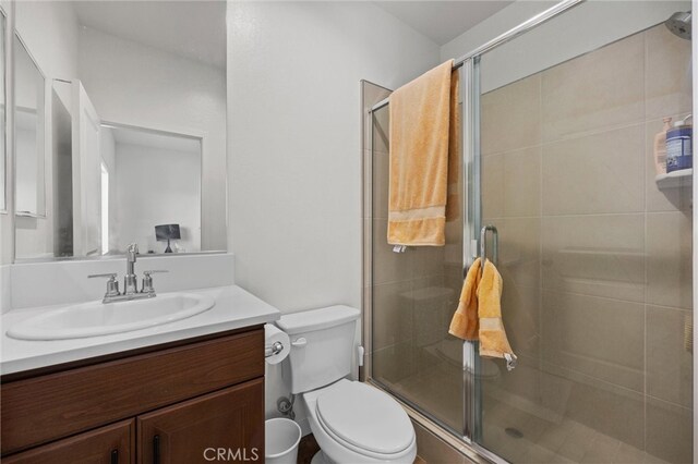 bathroom with toilet, a shower with shower door, and vanity