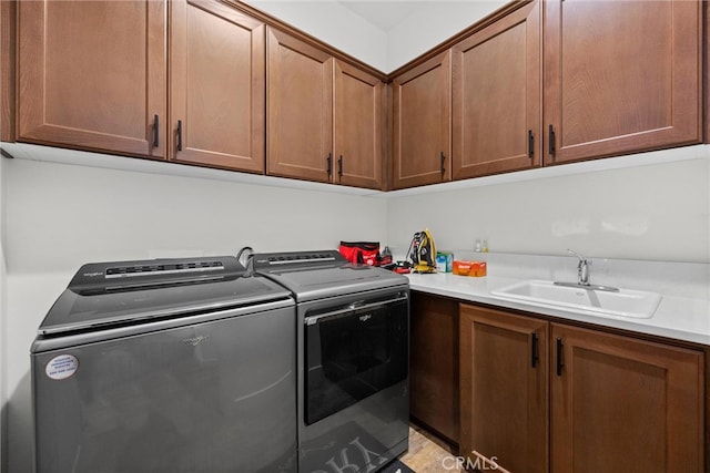 clothes washing area featuring cabinets, sink, and washing machine and clothes dryer