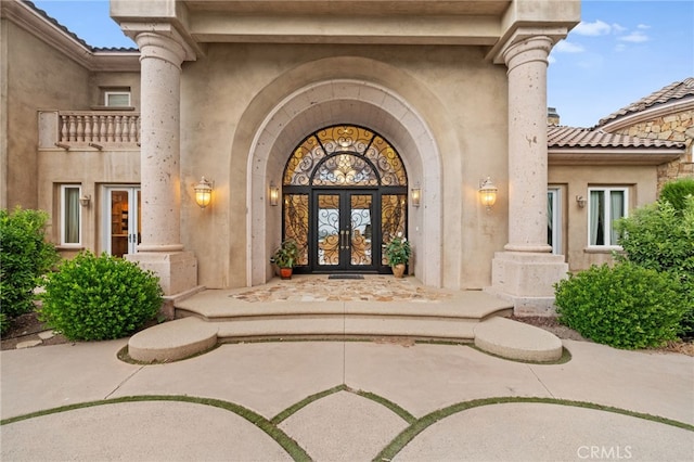 view of exterior entry featuring french doors and a balcony