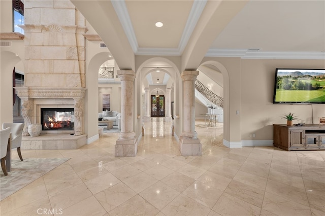 foyer entrance with a multi sided fireplace, decorative columns, a wealth of natural light, and ornamental molding