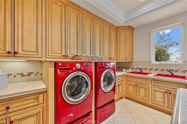 laundry room with cabinets, ornamental molding, sink, and washing machine and dryer