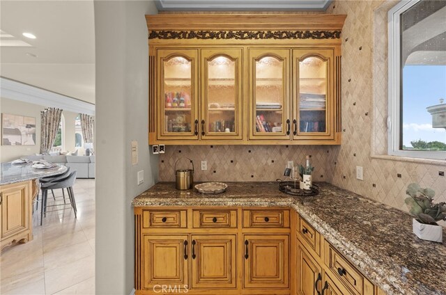 bar with light tile patterned floors, backsplash, tile walls, and dark stone countertops