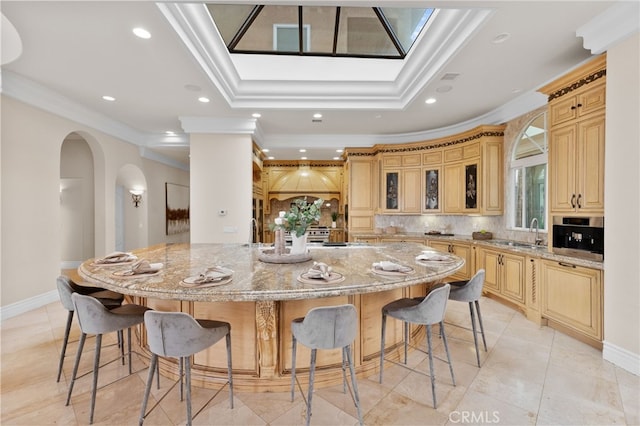 kitchen with a kitchen breakfast bar, decorative backsplash, a spacious island, and light stone countertops