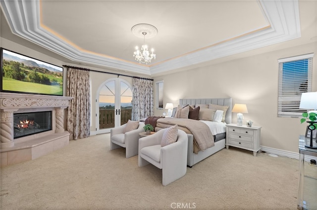 carpeted bedroom featuring a tile fireplace, french doors, an inviting chandelier, and a raised ceiling