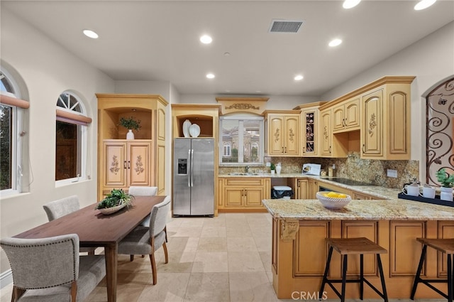 kitchen with sink, tasteful backsplash, kitchen peninsula, stainless steel fridge, and light brown cabinetry