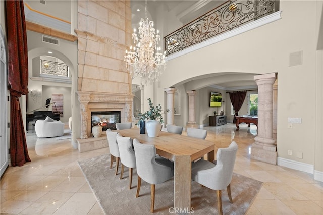 tiled dining space featuring decorative columns, a towering ceiling, and a tiled fireplace