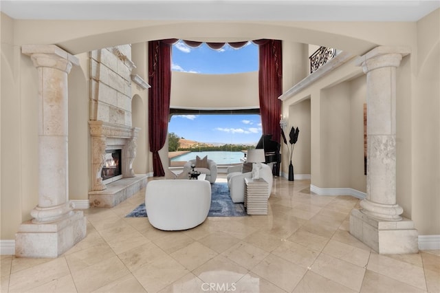 interior space featuring a healthy amount of sunlight, a water view, ornate columns, and a tile fireplace