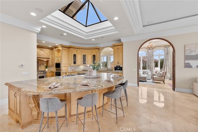 kitchen with decorative backsplash, crown molding, a large island, and a notable chandelier