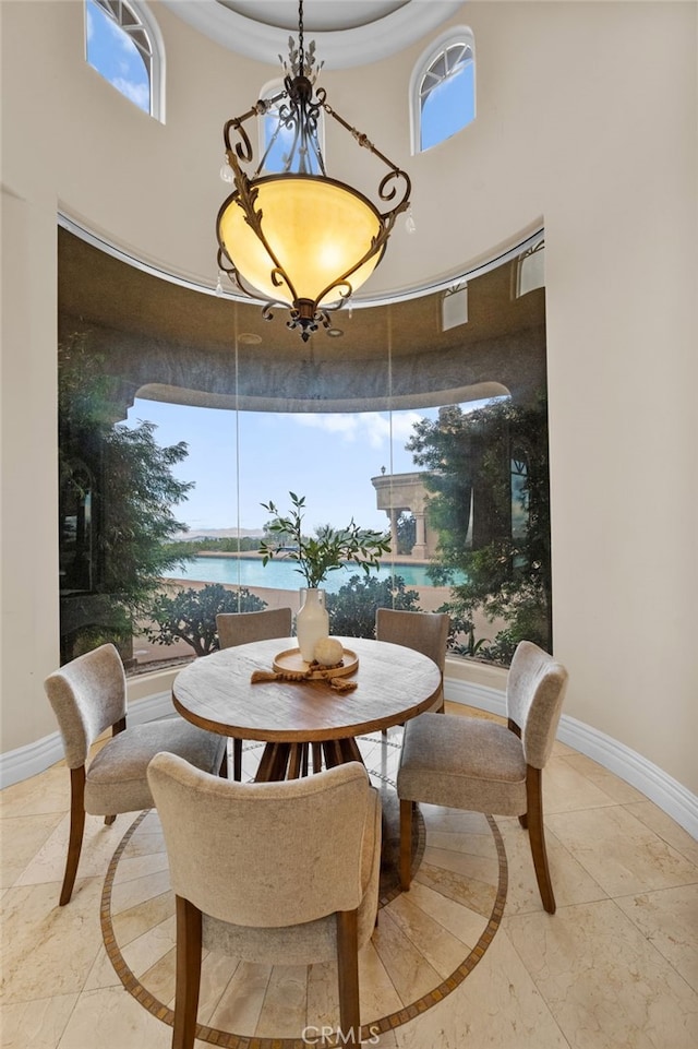 dining area featuring a water view and a towering ceiling