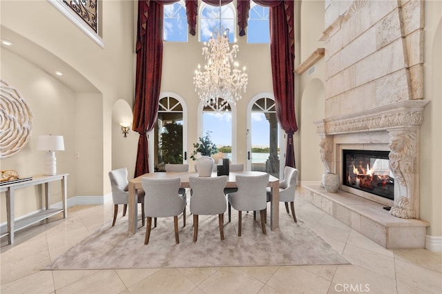 tiled dining area with a chandelier, a high ceiling, and a tiled fireplace