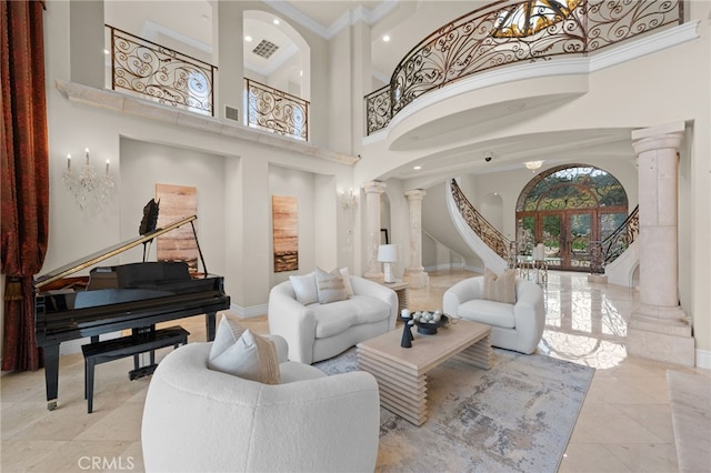 living room featuring a healthy amount of sunlight, ornate columns, and a towering ceiling