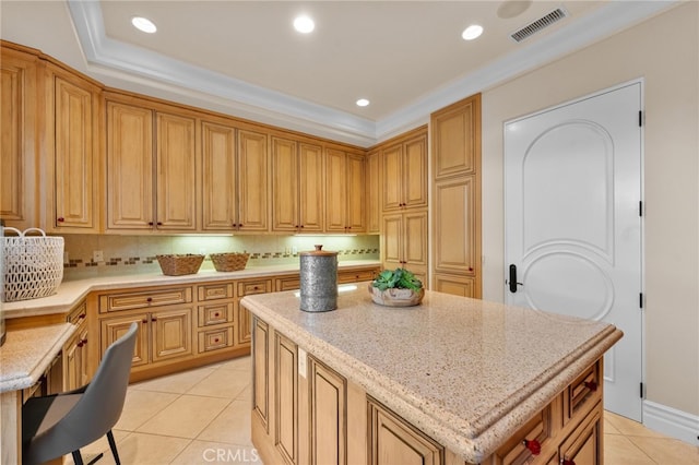 kitchen with decorative backsplash, light tile patterned floors, a kitchen bar, and a kitchen island