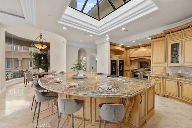 kitchen featuring light stone countertops, tasteful backsplash, crown molding, and a large island