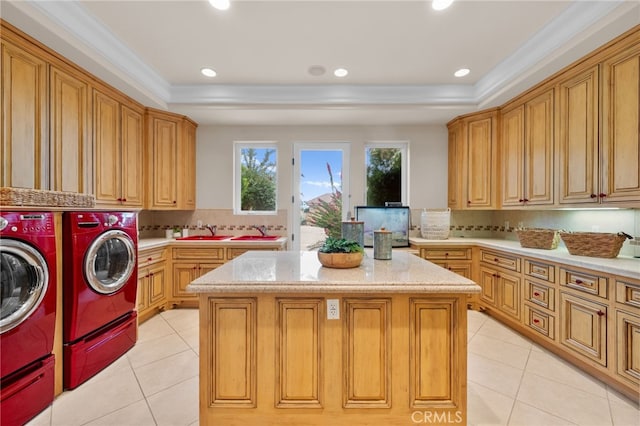 clothes washing area with cabinets, ornamental molding, sink, light tile patterned floors, and washing machine and dryer