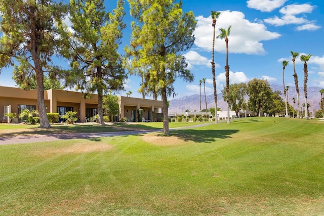 surrounding community with a mountain view and a lawn