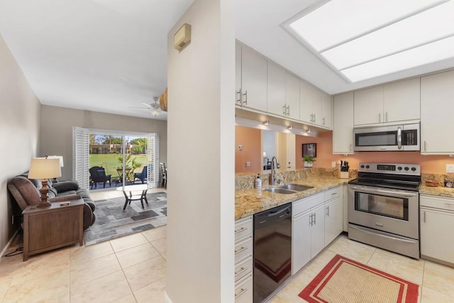 kitchen with sink, ceiling fan, light tile patterned floors, light stone counters, and stainless steel appliances