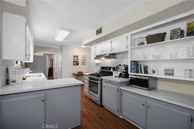 kitchen with white cabinets, kitchen peninsula, dark wood-type flooring, and appliances with stainless steel finishes