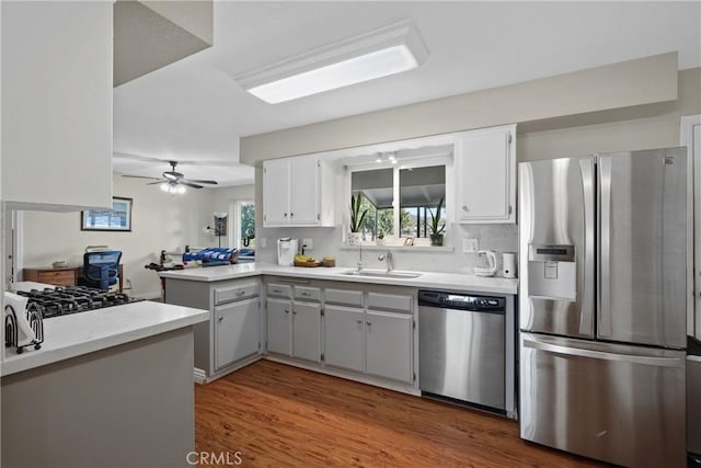 kitchen with sink, ceiling fan, dark hardwood / wood-style flooring, kitchen peninsula, and stainless steel appliances