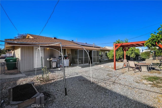 rear view of house with solar panels, a patio area, and a pergola