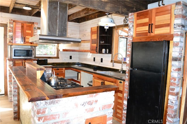 kitchen with island exhaust hood, light hardwood / wood-style flooring, sink, black appliances, and butcher block countertops