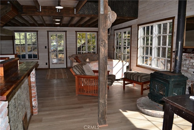 sunroom with vaulted ceiling with beams, a wood stove, and wood ceiling