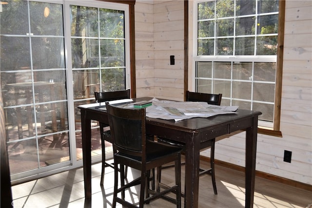 dining space with wood walls and wood-type flooring