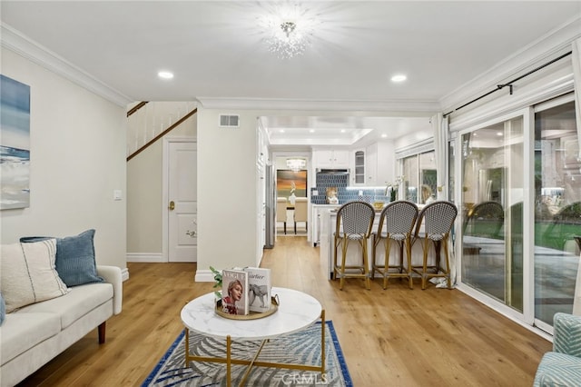 living room featuring crown molding, an inviting chandelier, and light wood-type flooring