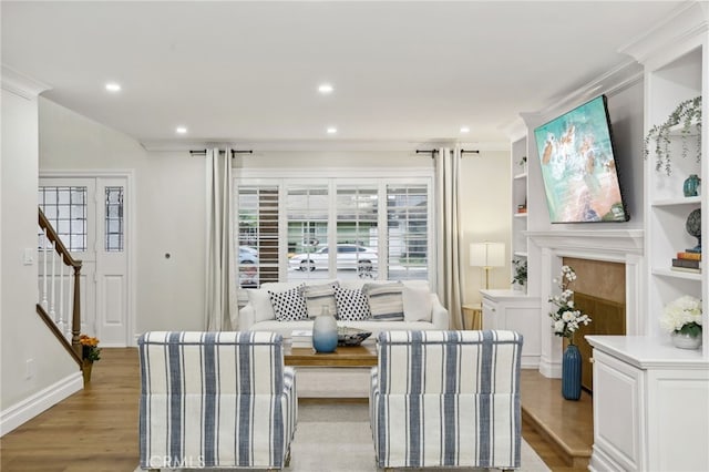 living room with light hardwood / wood-style floors, crown molding, and a fireplace