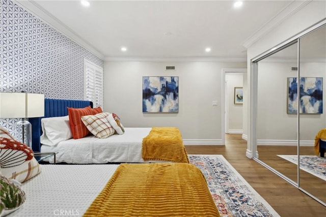 bedroom with wood-type flooring, a closet, and crown molding