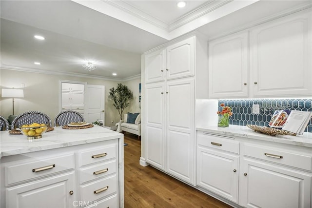 kitchen featuring light stone countertops, dark hardwood / wood-style flooring, white cabinetry, and crown molding