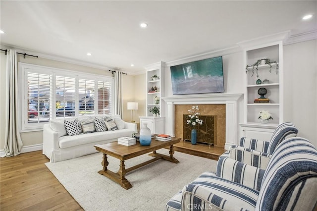 living room featuring crown molding, built in features, and light wood-type flooring