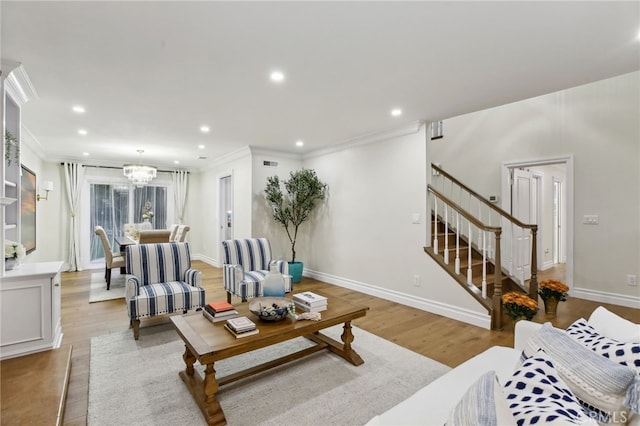 living room with light wood-type flooring, ornamental molding, and an inviting chandelier