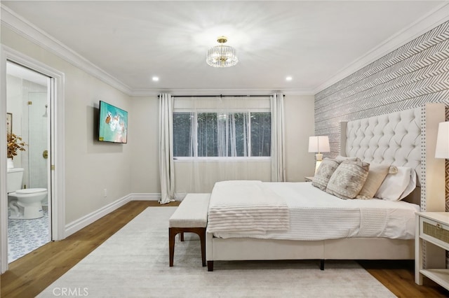 bedroom featuring ensuite bathroom, wood-type flooring, ornamental molding, and an inviting chandelier