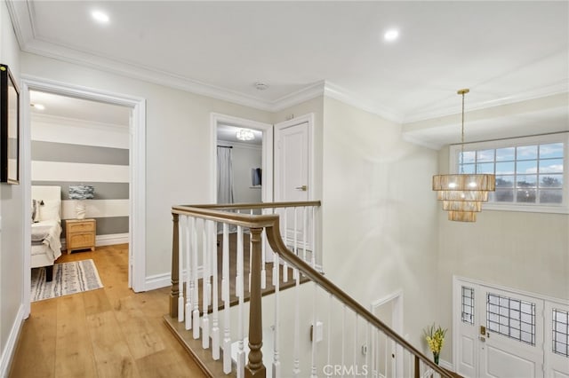 hallway featuring an inviting chandelier, light hardwood / wood-style floors, and ornamental molding