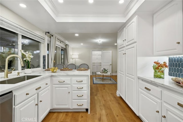 kitchen with kitchen peninsula, sink, light hardwood / wood-style flooring, dishwasher, and white cabinetry