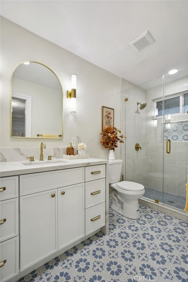 bathroom featuring vanity, toilet, and a shower with shower door