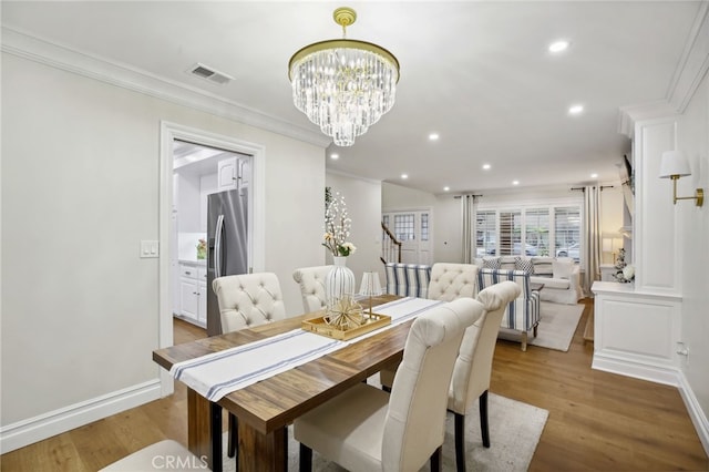 dining room featuring wood-type flooring, an inviting chandelier, and crown molding