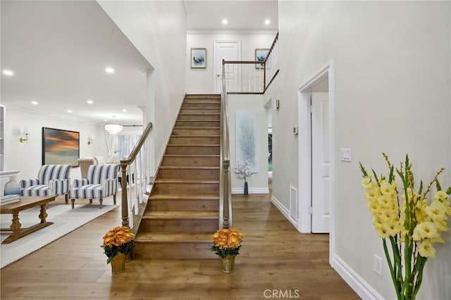 stairs with hardwood / wood-style floors and crown molding