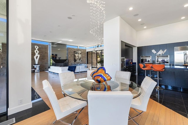 dining room with hardwood / wood-style floors, a towering ceiling, and an inviting chandelier