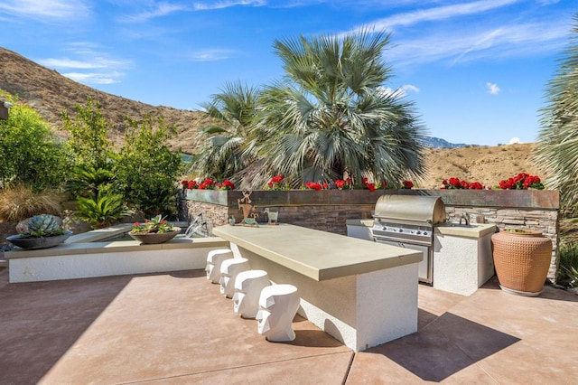 view of patio with a mountain view, grilling area, and exterior kitchen