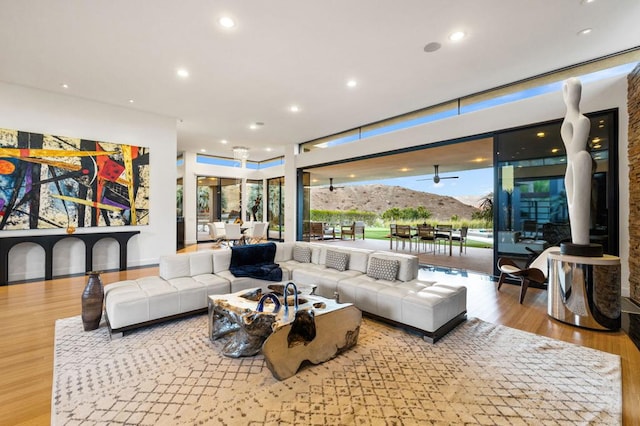 living room featuring a mountain view, light hardwood / wood-style floors, a wealth of natural light, and ceiling fan