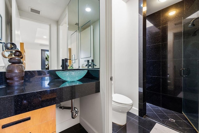 bathroom with tile patterned floors, toilet, walk in shower, and sink